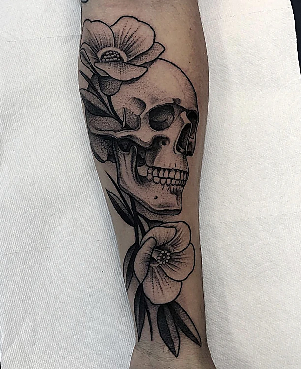 Calavera con flores en negro, con trazo de grabado, en el antebrazo